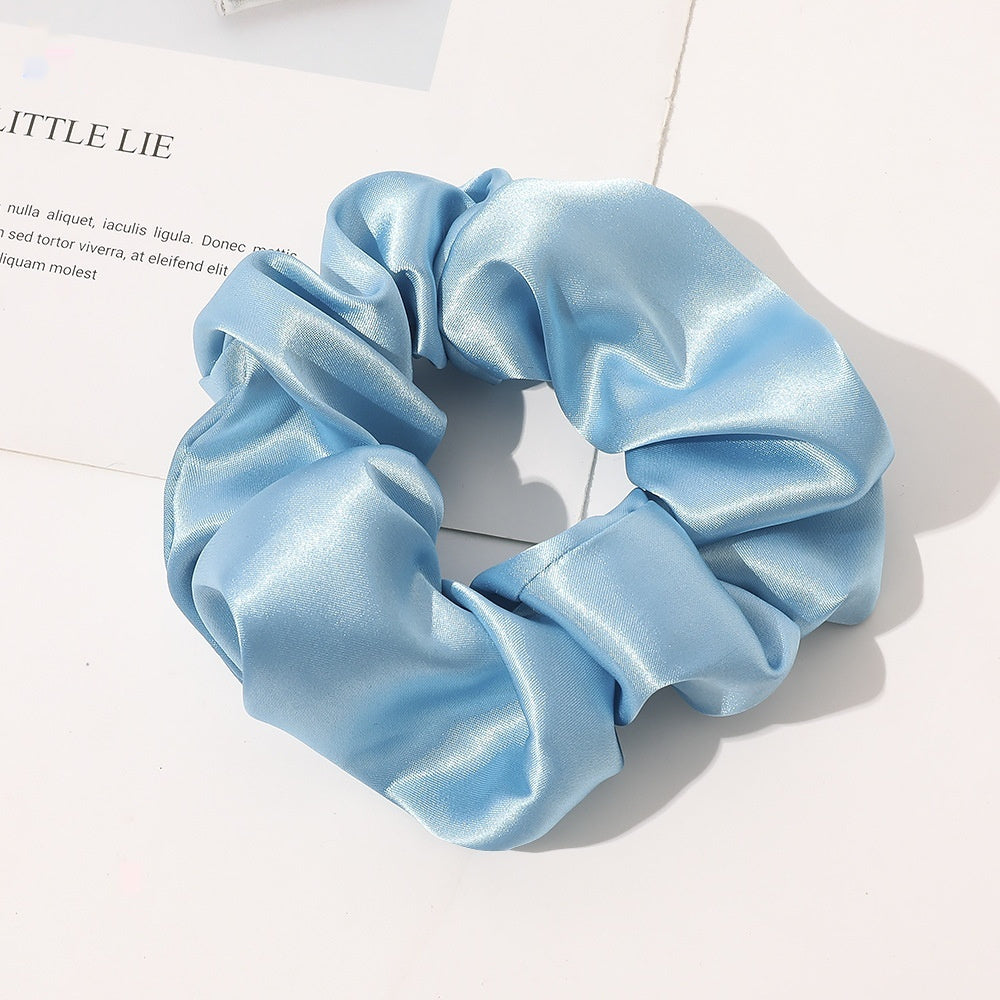 Chouchou en satin de soie couleur bleu clair posé sur fond blanc