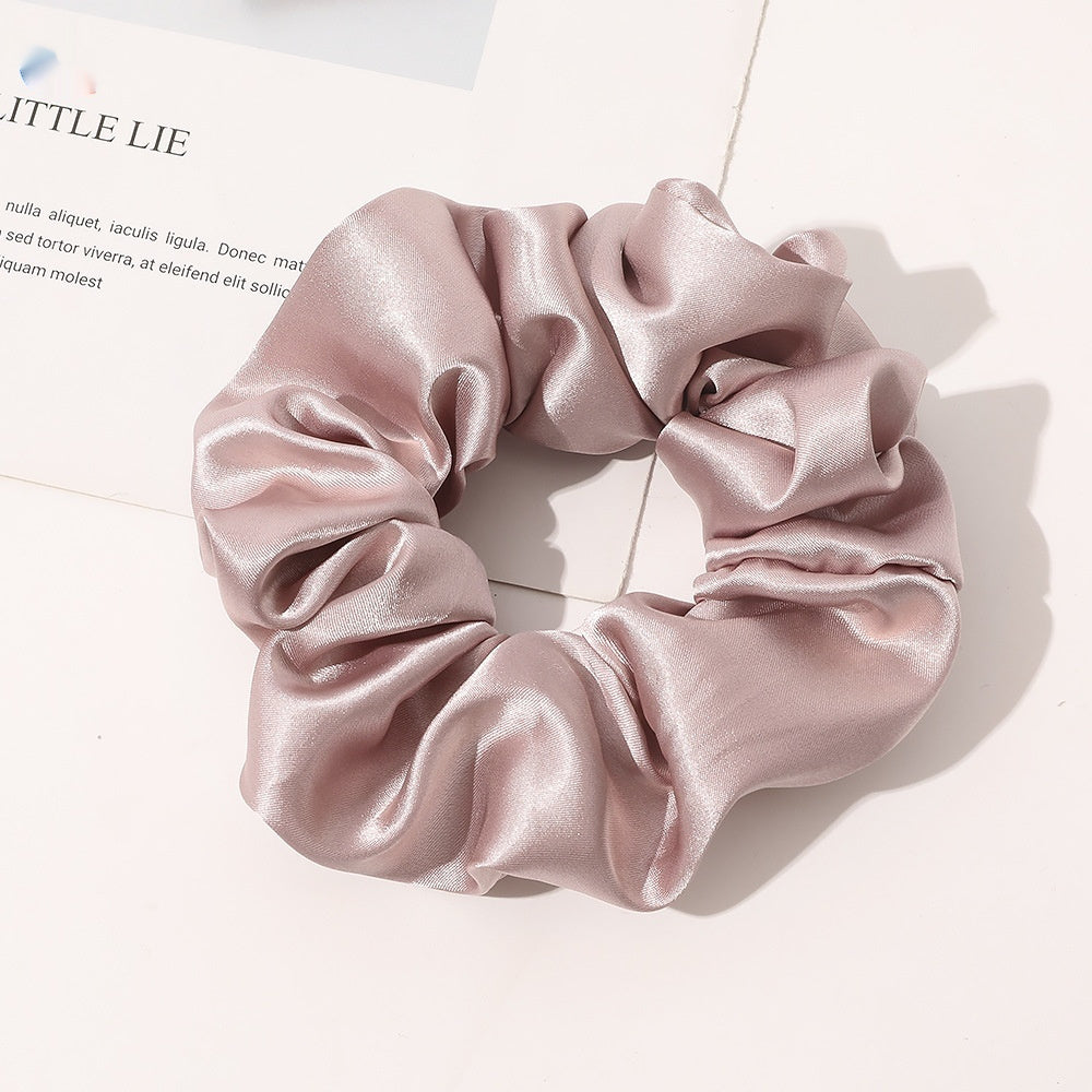 Chouchou en satin de soie couleur beige rose posé sur fond blanc
