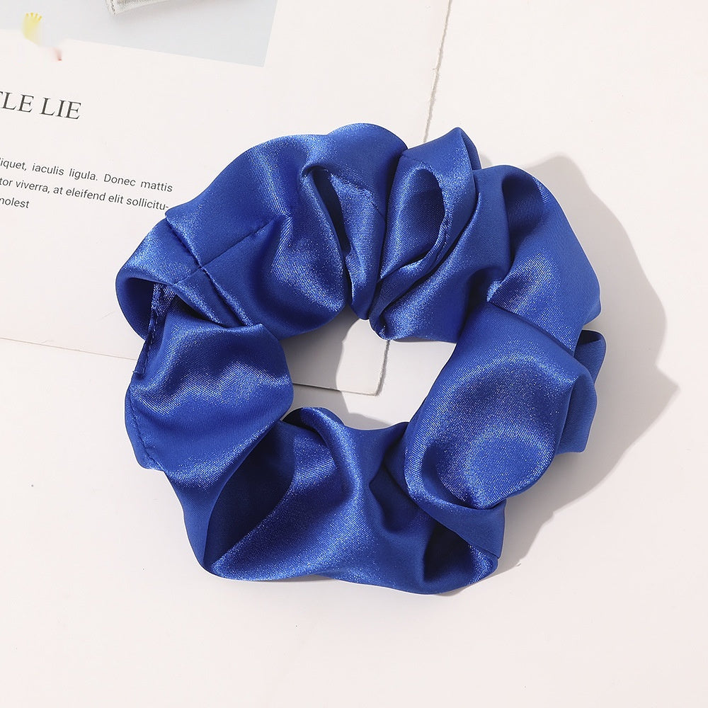 Chouchou en satin de soie couleur bleu posé sur fond blanc