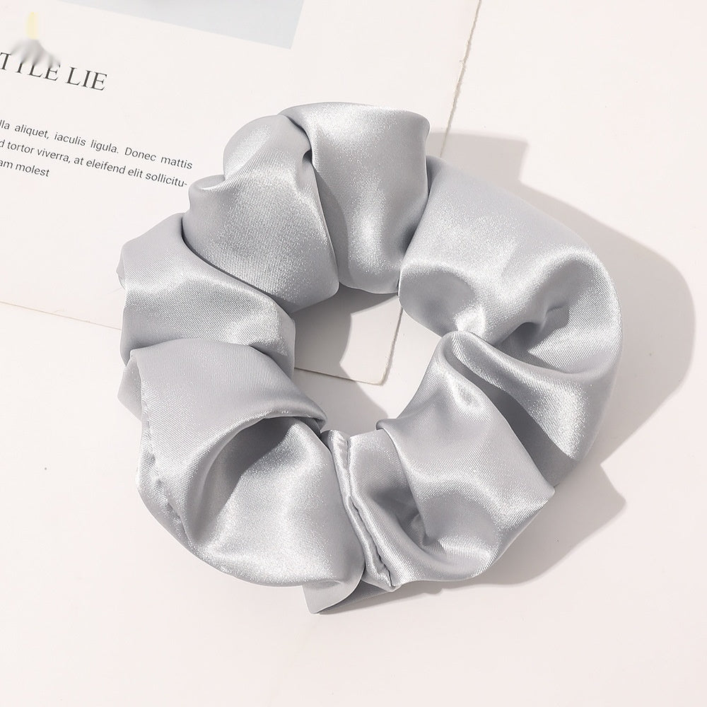 Chouchou en satin de soie couleur gris clair posé sur fond blanc