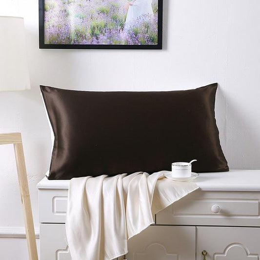 Oreiller de couleur marron foncé en satin de soie doux et hydratant pour la peau et le visage posé sur un meuble 