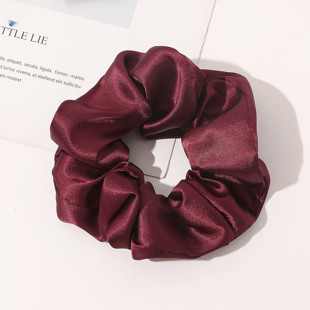 Chouchou en satin de soie couleur rouge Bordeaux posé sur fond blanc 